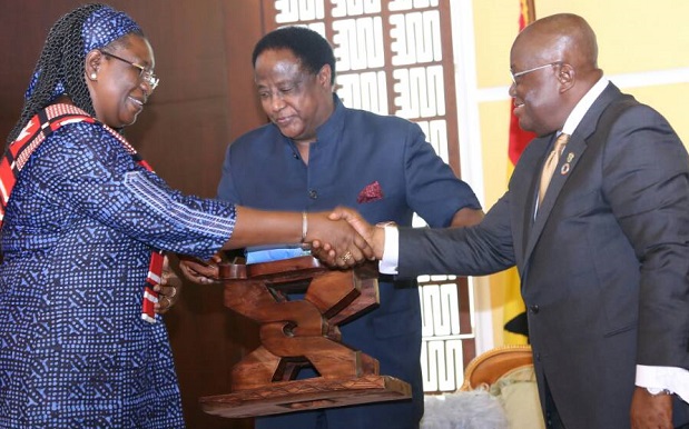 President Akufo-Addo presenting a gift to Me Clemence Some Troare, out-going Burkina Ambassador to Ghana. Looking on is Mr Ahmed Alhassan (middle), Director, State Protocol